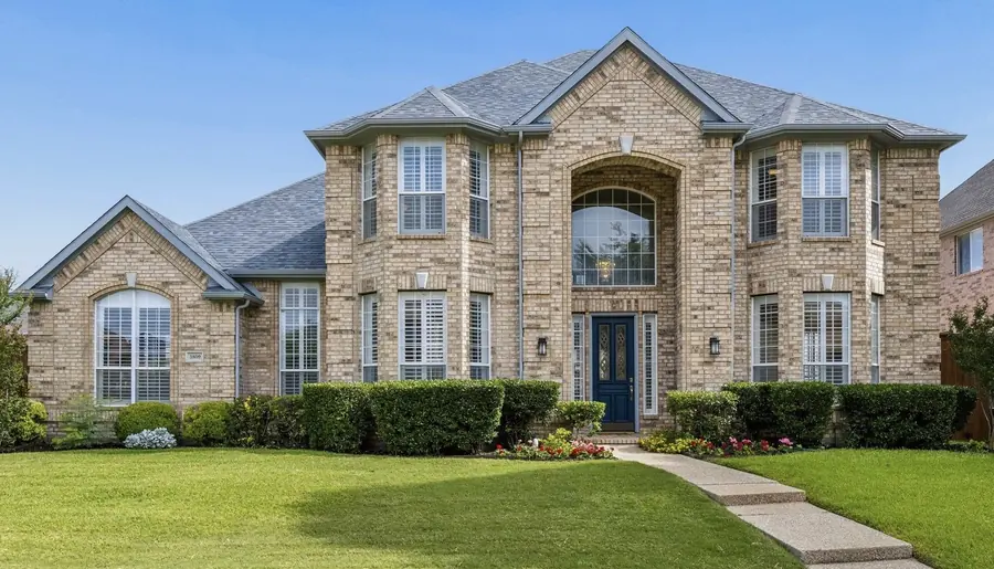 Two-story stone home with a green front lawn